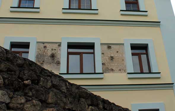 участки стены на фасаде здания, где остались следы от пуль